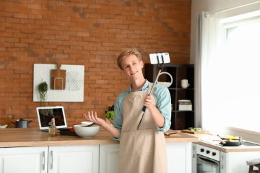 Yakışıklı genç adam mutfakta yemek pişirme videosu dersi kaydediyor.