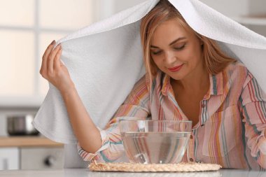 Kadın burun deliklerini rahatlatmak ve açmak için evde buhar solunumu yapıyor.