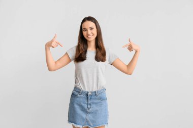 Açık arkaplanda şık tişörtler giyen güzel bir kadın.