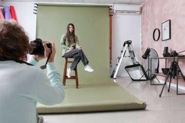 Stüdyoda kadın modelin fotoğrafını çeken fotoğrafçı.