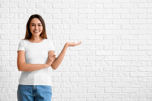 Ung Kvinna Blank Shirt Visar Något Vit Tegel Bakgrund — Stockfoto