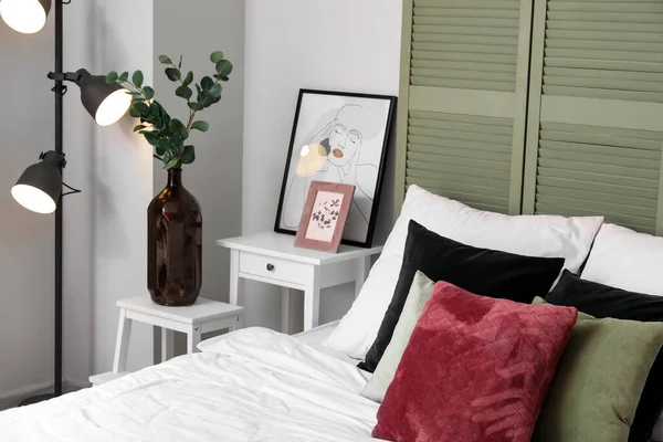 Interior of light bedroom with green folding screen and table