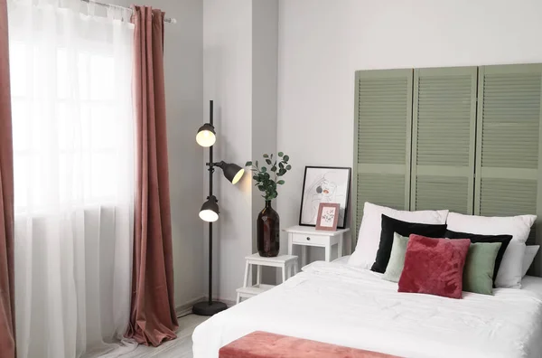 Interior of light bedroom with green folding screen and glowing lamp