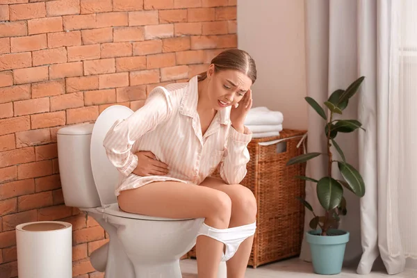 浴室的马桶上坐着腹泻的年轻女人 — 图库照片