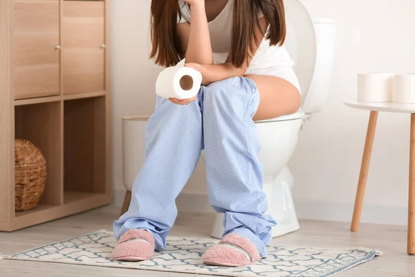 洗手间里的马桶上坐着纸卷的年轻女人 — 图库照片