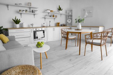 Şık mutfak masasında taze elmalarla dolu bir sepet.