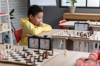 Kulüpte turnuvada satranç oynayan küçük Afro-Amerikalı çocuk.
