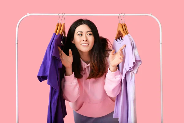 Ung Asiatisk Kvinna Och Rack Med Shirts Rosa Bakgrund — Stockfoto