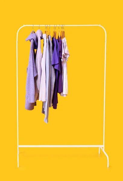 Стойка Одеждой Фиолетовых Оттенках Желтом Фоне — стоковое фото