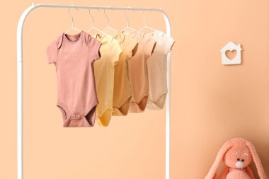 Bej duvarın yanındaki odada bebek kıyafetleriyle dizilin.