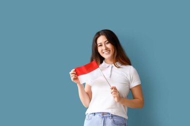 Mavi arka planda Endonezya bayrağı olan genç Asyalı kadın.