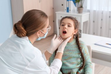 Doktor klinikte boğazı ağrıyan küçük bir kızı muayene ediyor.