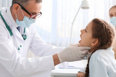 Doktor klinikte boğazı ağrıyan küçük bir kızı muayene ediyor.