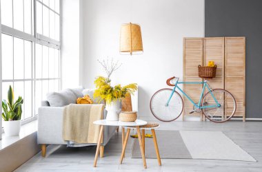 İçinde vazo, kanepe ve bisiklet çiçekleri olan modern oturma odası.