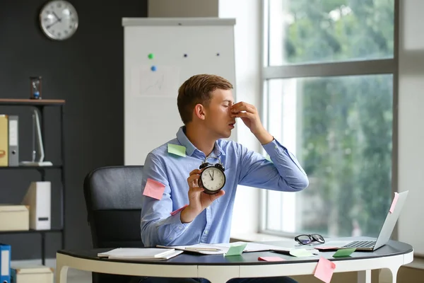 Trött Ung Man Med Svart Väckarklocka Och Klibbiga Anteckningar Sitter — Stockfoto