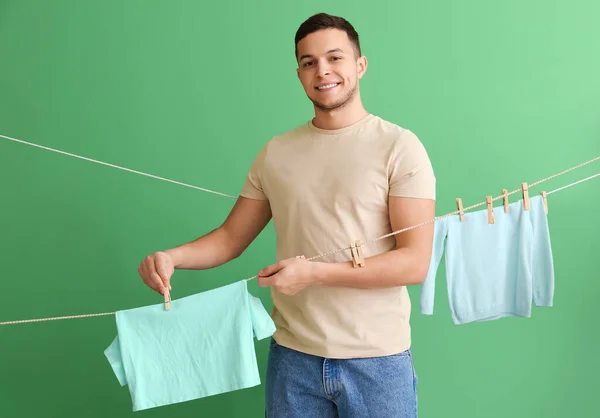 Young Man Hanging Children Laundry Clothespins Green Background — Stock Photo, Image