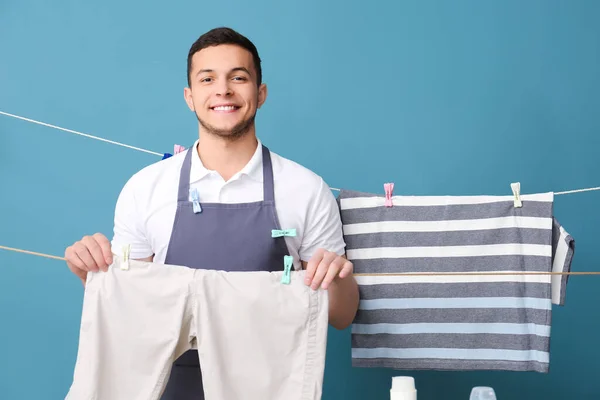 Young Man Hanging Clean Laundry Clothespins Blue Background — Stock Photo, Image