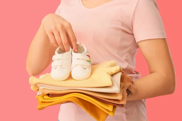 Vrouw Met Stapel Van Baby Kleding Laarsjes Roze Achtergrond Closeup — Stockfoto