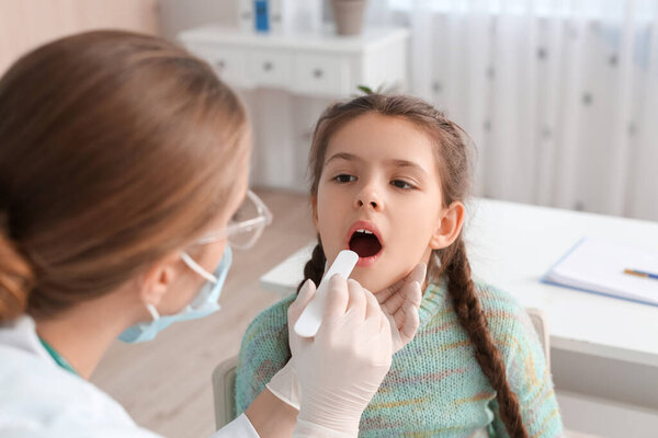 Doctor examining little girl with sore throat in clinic