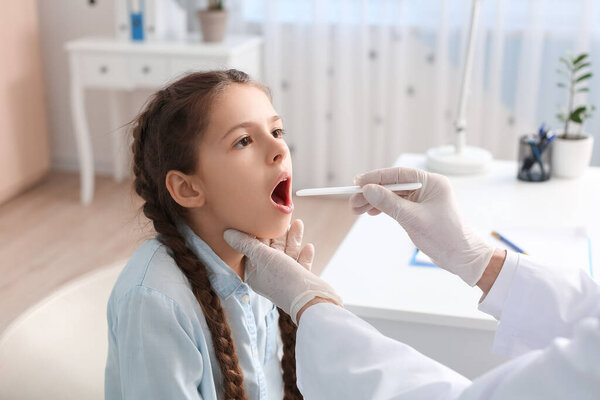Doctor examining little girl with sore throat in clinic