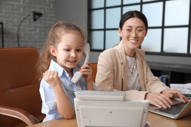 Küçük kızıyla birlikte ofiste çalışan genç bir anne.