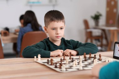 Kulüpte turnuvada satranç oynayan küçük çocuk.