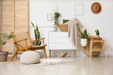 Koltuğu, göğsü ve çiçekleri olan hafif oturma odasının içinde.