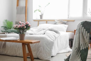 Begonya çiçekleri, dizüstü bilgisayar ve dergi ışık odasındaki rahat yatağın yanında.