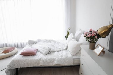 İçinde begonya çiçekleri olan çekmeceler ve iç odada rahat bir yatak.