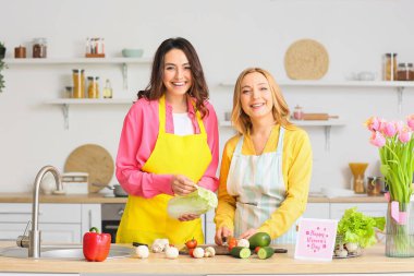 Mutlu genç bir kadın ve annesi evde birlikte yemek pişiriyorlar. Uluslararası Kadınlar Günü kutlamaları