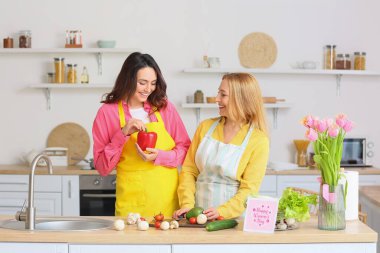 Mutlu genç bir kadın ve annesi evde birlikte yemek pişiriyorlar. Uluslararası Kadınlar Günü kutlamaları