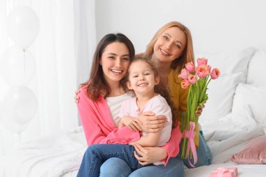 Genç kadın, küçük kızı ve annesi evde Uluslararası Kadınlar Günü 'nde çiçeklerle birlikte.