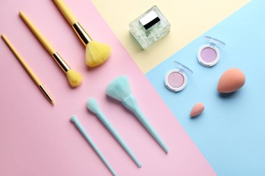 Renk arkaplan üzerinde farklı kozmetik ürünleri ve makyaj fırçaları içeren kompozisyon