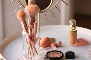 Masada farklı kozmetik ürünler ve makyaj fırçaları