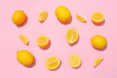 Pembe arka planda bir sürü olgun limon ve dilim var.