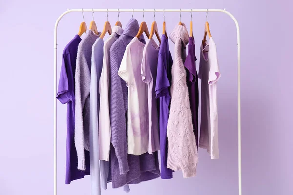 Regál Oblečením Purpurových Odstínech Šeříkovém Pozadí — Stock fotografie