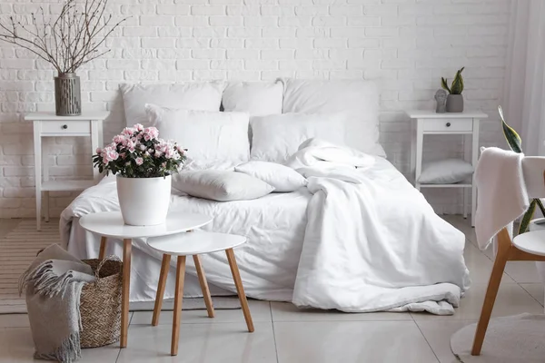 室内白砖墙边美丽的秋海棠花和舒适的床 — 图库照片