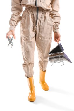 Beyaz arka planda araçları olan koruyucu kıyafetli kadın arıcı.