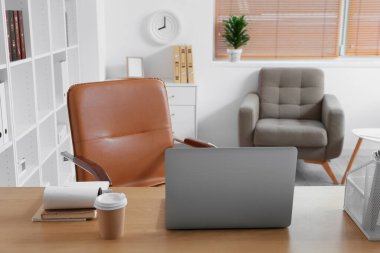 Modern laptop ve kağıt kahve fincanı ofisteki masada.