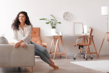 Güzel çıplak ayaklı kadın evdeki kanepede dinleniyor.