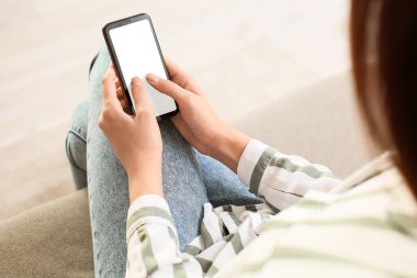 Kanepede oturan bir kadın cep telefonu ve mesaj okuyor, yakın plan.