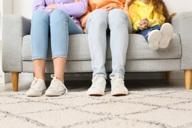 Genç bir aile evdeki kanepede oturuyor.