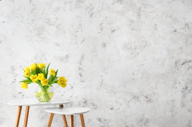 Vazoda çiçekli sehpalar ışık duvarının yanında.