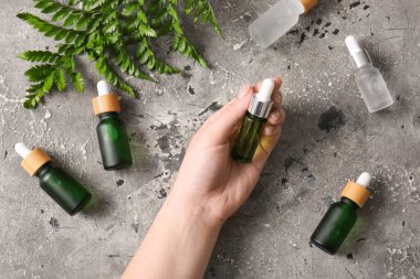 Gri grunge arka planında serum şişeleri olan bir kadın el.