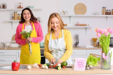 Genç bir kadın mutfakta Uluslararası Kadınlar Günü için annesini selamlıyor.