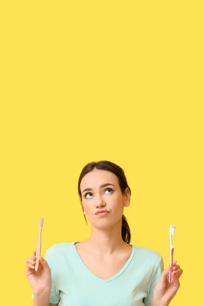 Sarı Arka Planda Diş Fırçası Olan Düşünceli Genç Bir Kadın — Stok fotoğraf