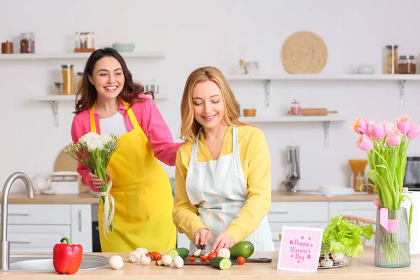 Genç bir kadın mutfakta Uluslararası Kadınlar Günü için annesini selamlıyor.