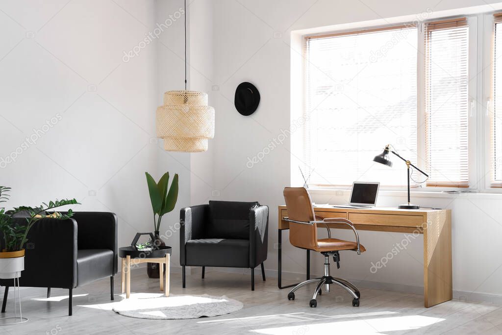 Interior of modern office with workplace and black armchairs