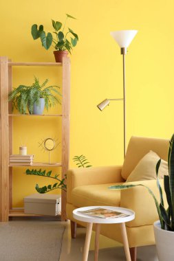 Kitaplığı, koltuğu ve lambası olan parlak oturma odasının içinde.