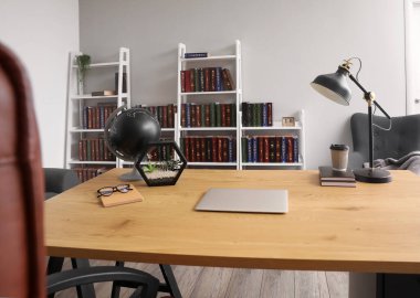 Ev kütüphanesinde modern dizüstü bilgisayarı olan şık bir iş yeri